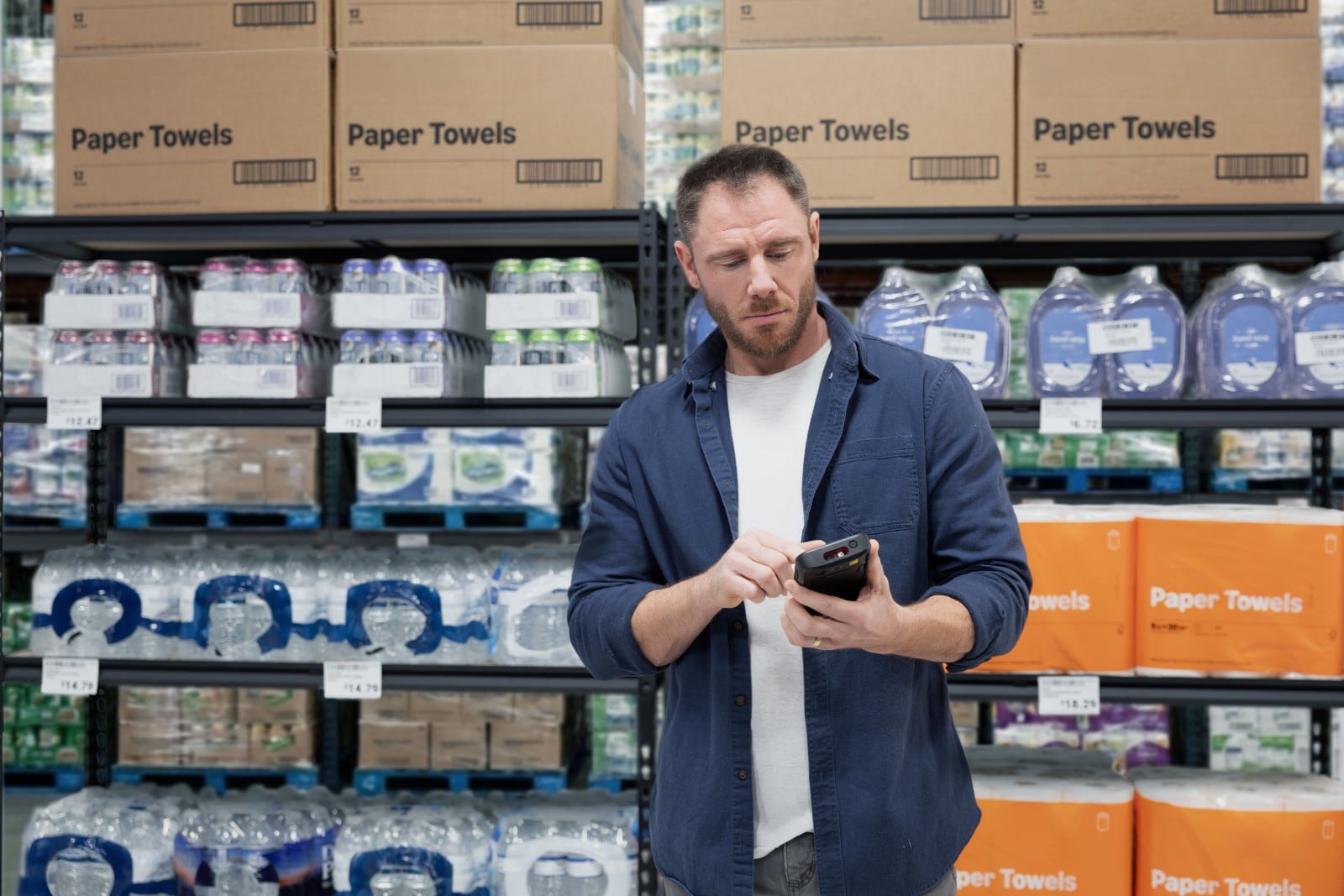 Pracownik sklepu wielkopowierzchniowego sprawdza towar na regale terminalem Honeywell CT70