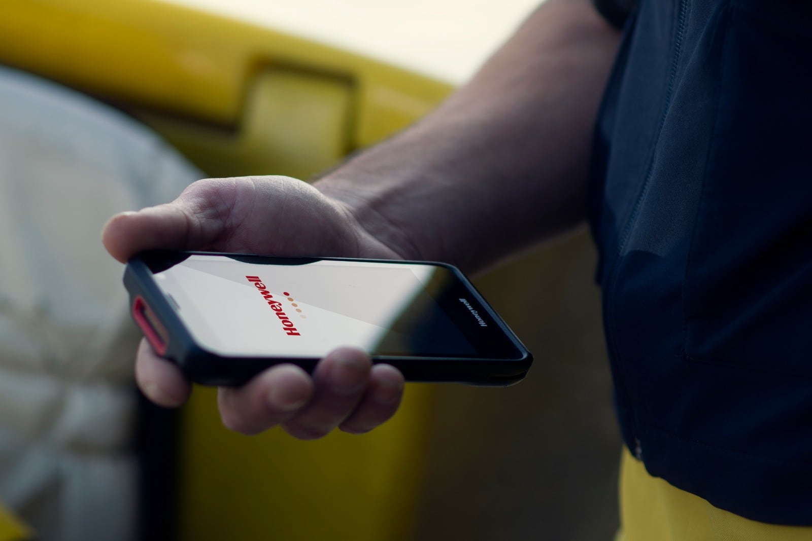 Kurier obsługuje terminal Honeywell ScanPal EDA52 przy żółtym pojeździe dostawczym