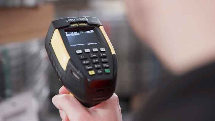 Operator trzyma czytnik Datalogic PowerScan 9600 z klawiaturą i wyświetlaczem OLED podczas pracy w magazynie