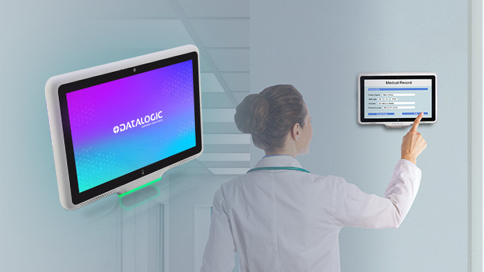 Pracowniczka przychodni obsługuje naścienny terminal Datalogic Smart Portal, na drugim urządzeniu na ścianie widoczny formularz kartoteki pacjenta