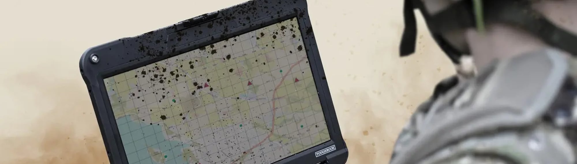Żołnierz pracuje na w pełni wzmocnionym laptopie Panasonic TOUGHBOOK 40 z mapą terenu, w kurzu i przy zachlapanej obudowie