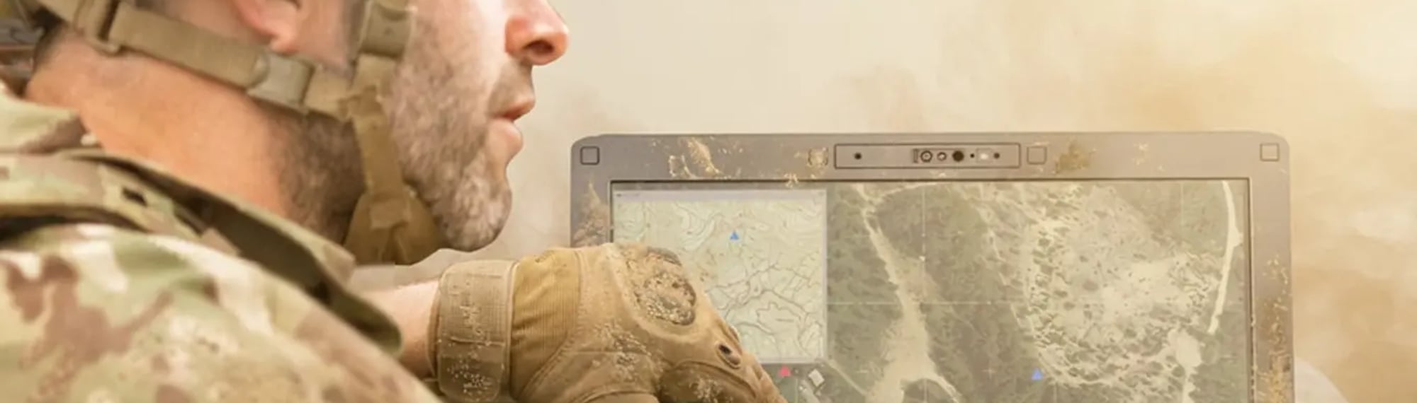 Żołnierz w rękawicach obsługuje zabłocony wzmocniony laptop Panasonic TOUGHBOOK z mapą terenu na ekranie