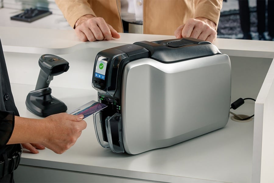 Pracownik podaje klientowi kartę wydrukowaną na drukarce Zebra ZC100 przy ladzie